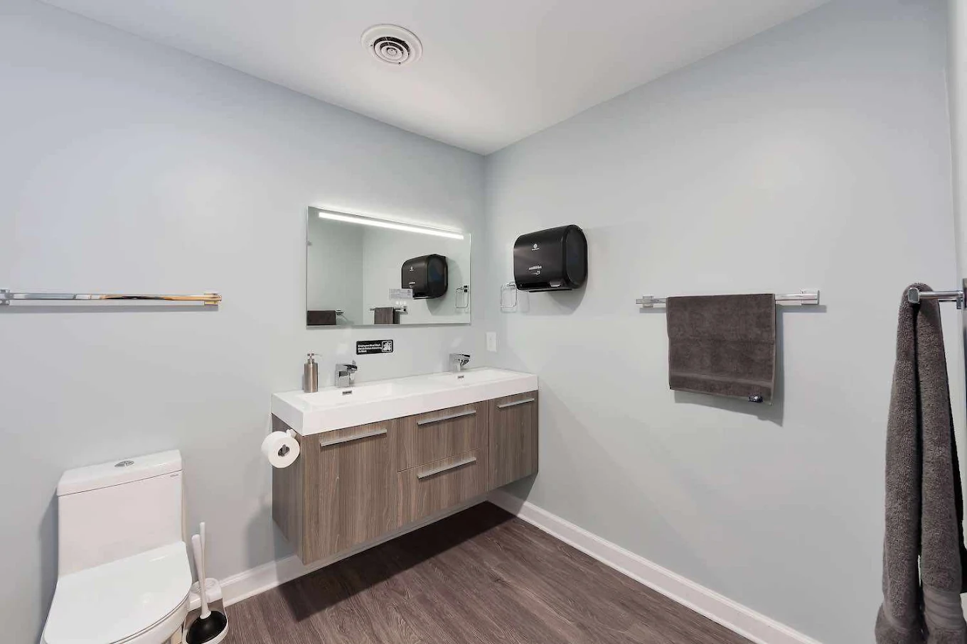 Bathroom with double-sink vanity, mirror, and towel racks