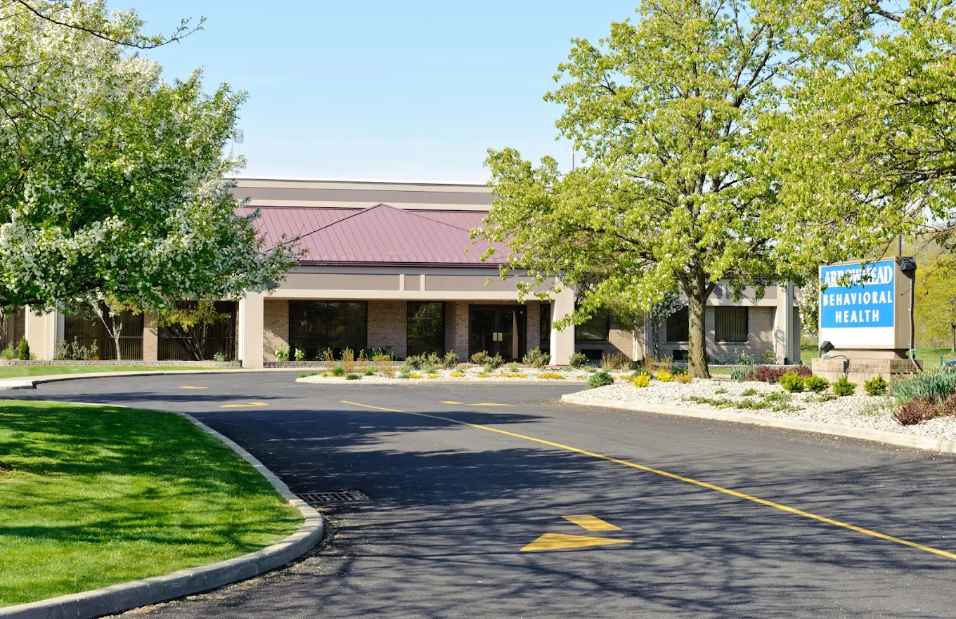 Driveway entrance and exterior of Arrowhead Behavioral Health facility surrounded by trees and greenery