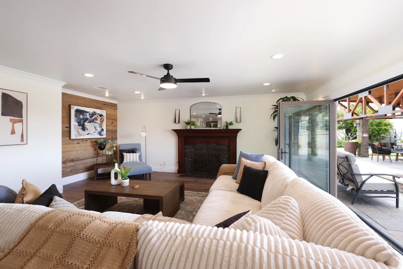 Bright living room with sectional sofas, fireplace, wood accents, and access to an outdoor patio