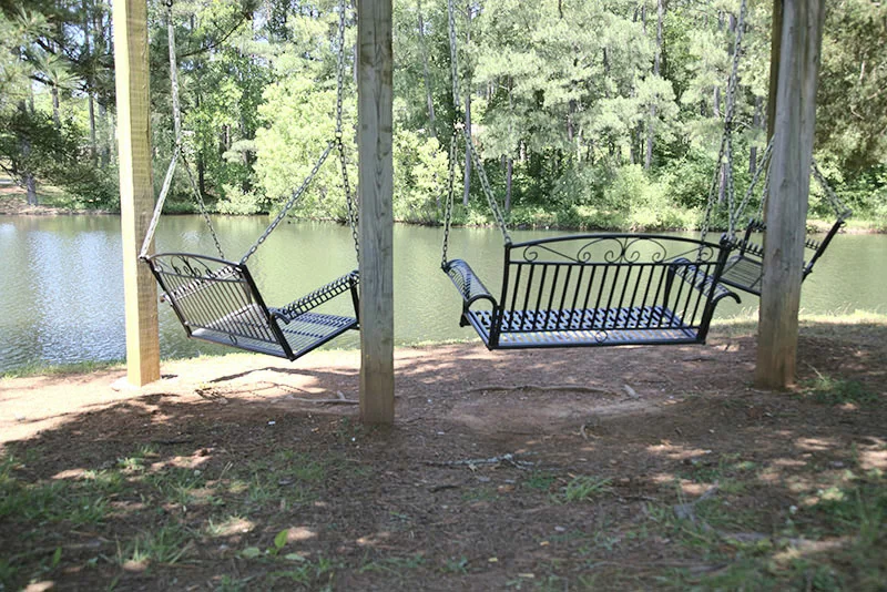 Two bench swings overlooking the lake from a wooded shore