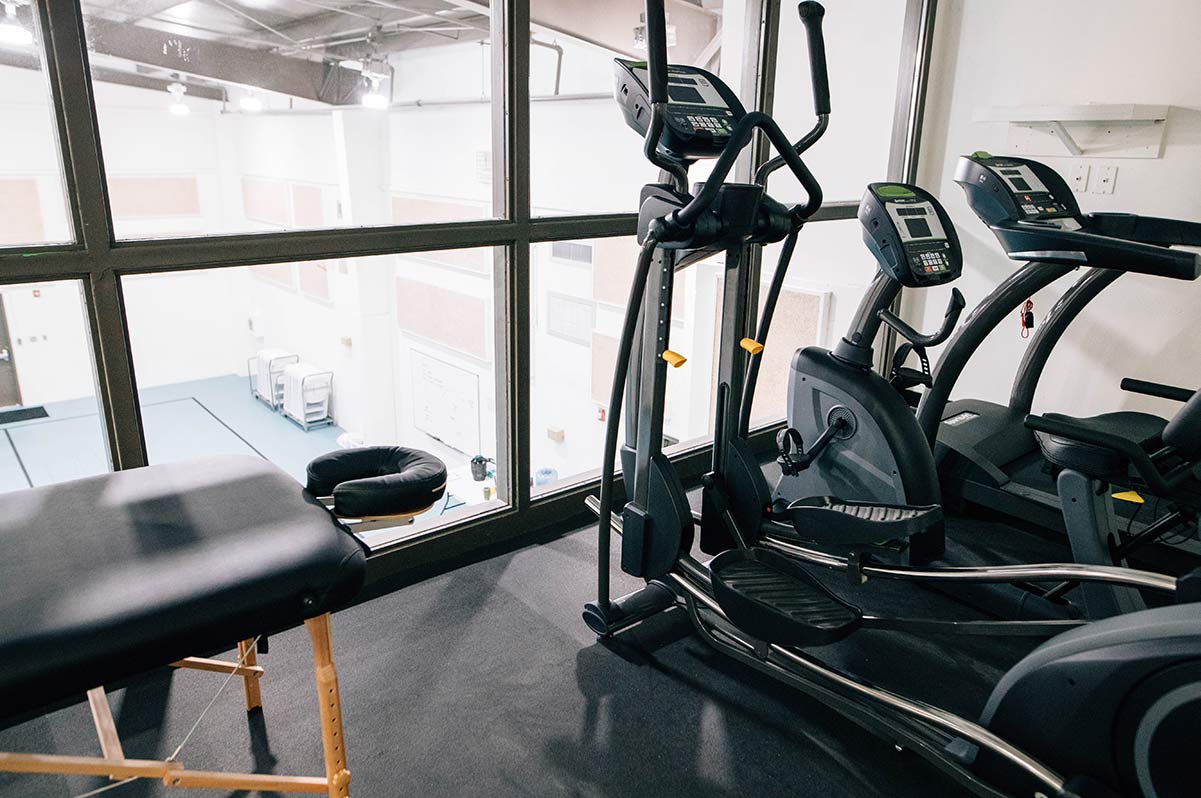Fitness room with cardio machines and massage table