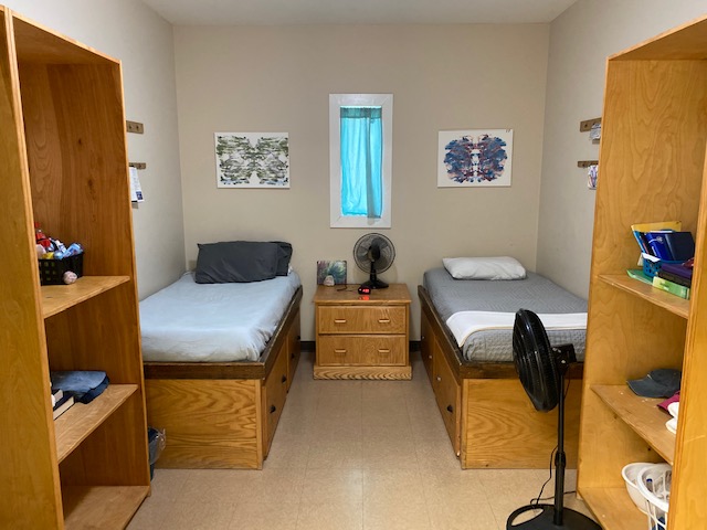 Shared bedroom with two beds and wooden storage shelves