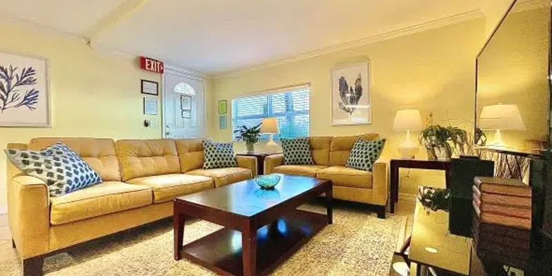  A cozy, well-lit living room featuring a large beige sectional sofa, a wooden coffee table, decorative pillows, and soft lighting from lamps.