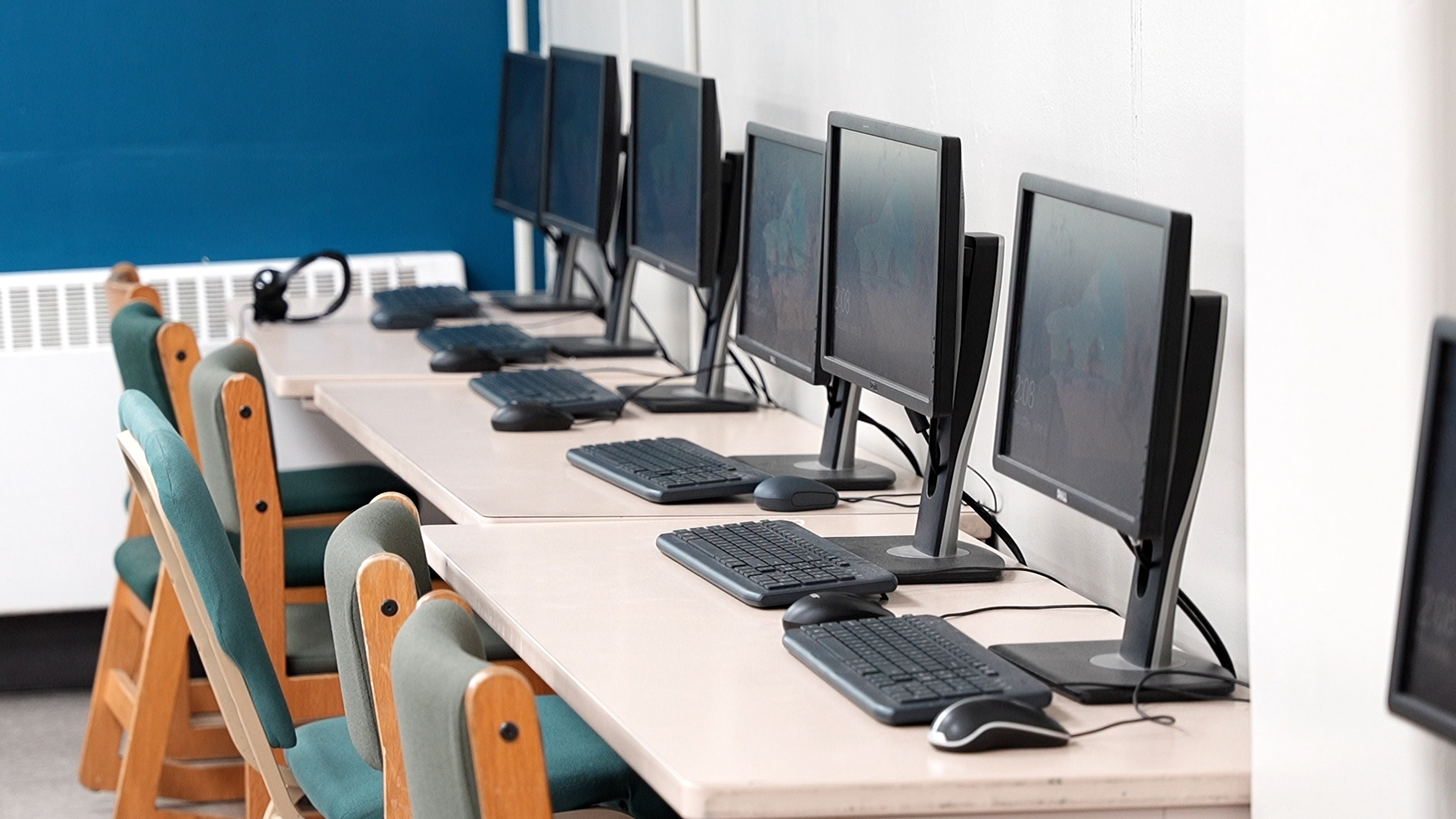 Row of desktop computers with chairs in a lab setting