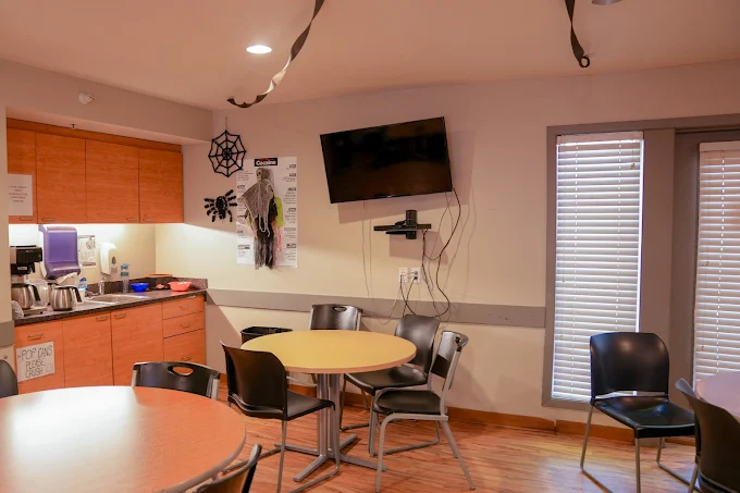 Kitchenette with round tables, chairs, and wall TV