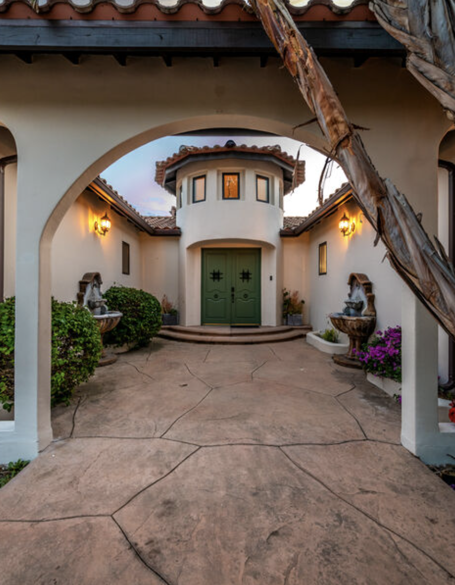 A grand entrance with an arched walkway and green doors.