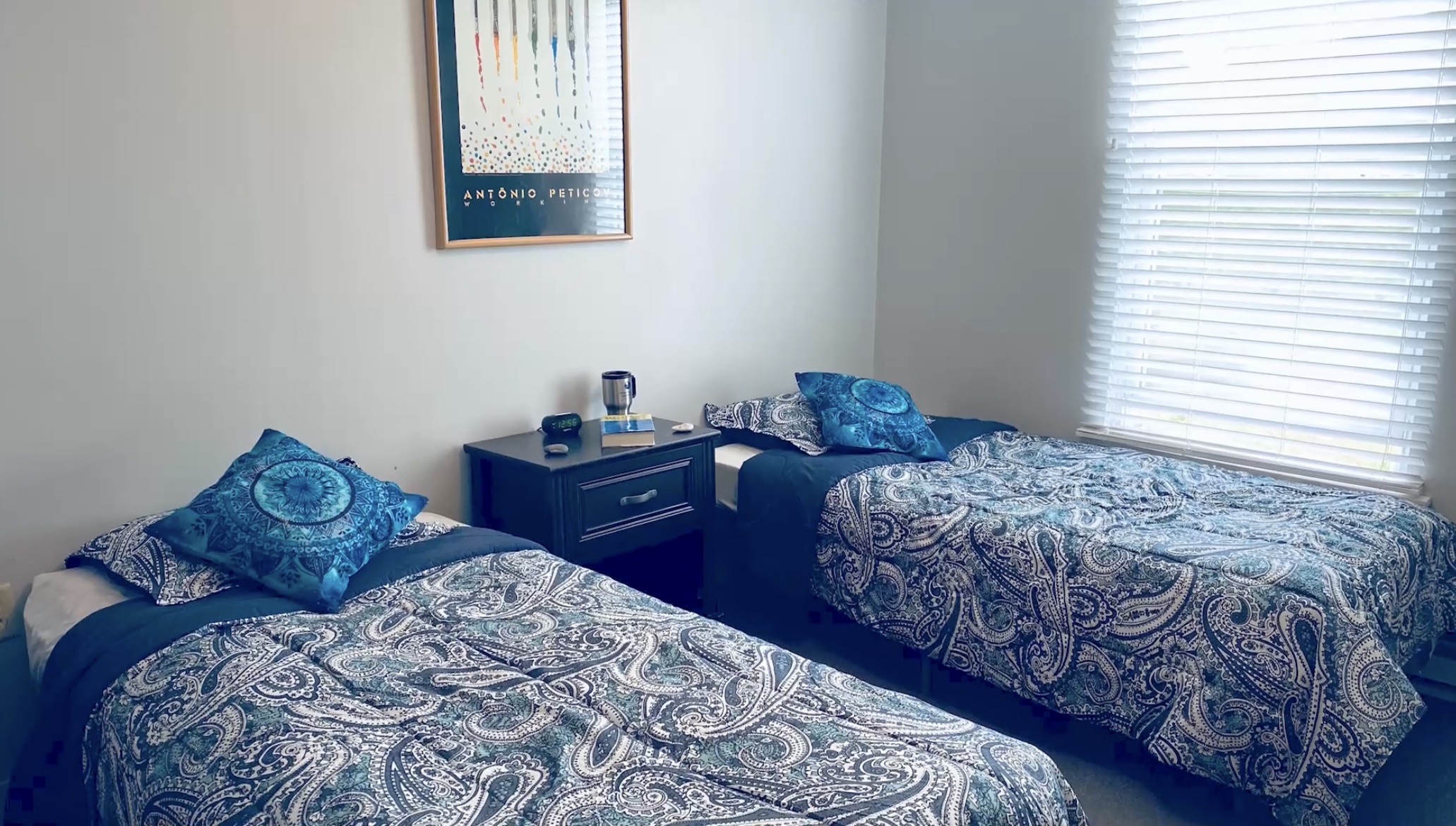 Two twin beds with blue paisley bedding by a window