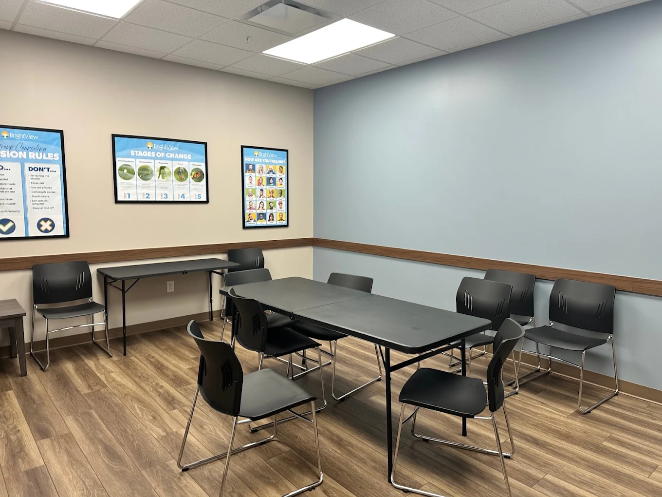 Group therapy room with tables, chairs, and wall posters