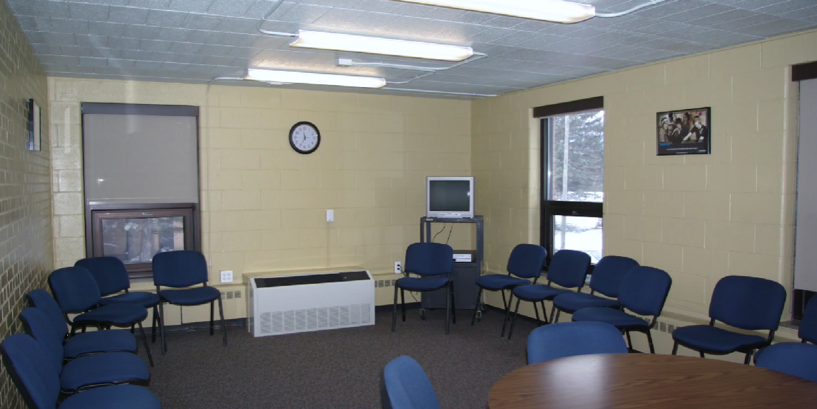 Circle of blue chairs around a TV for group counseling sessions
