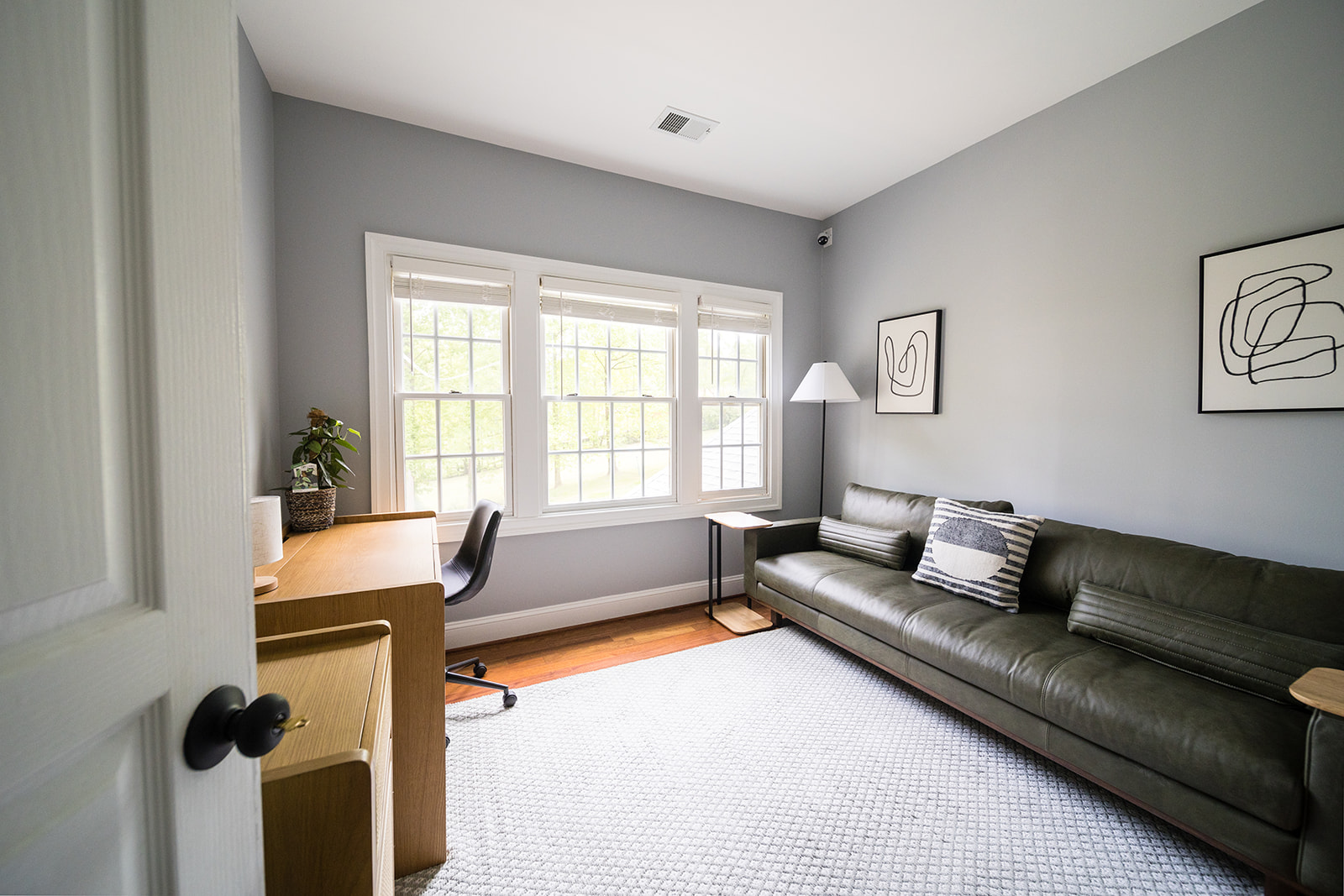 Bright private office with desk and green couch