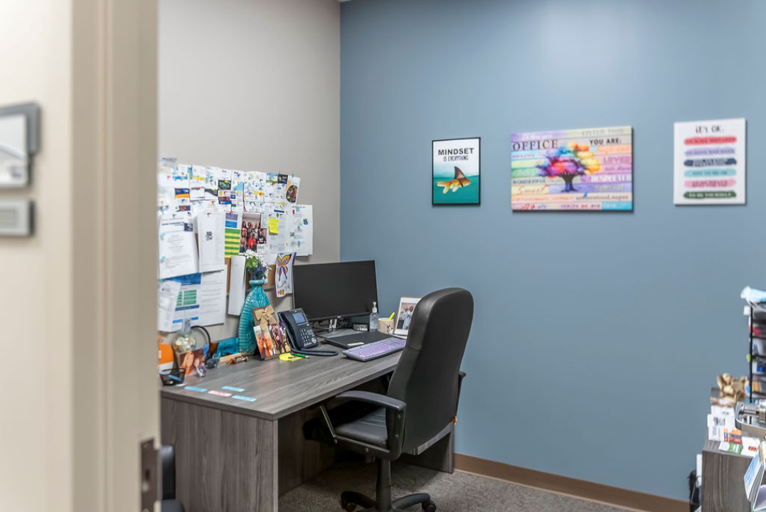 BrightView Health consultation room with desk, computer, office chair, bulletin board, and motivational wall art
