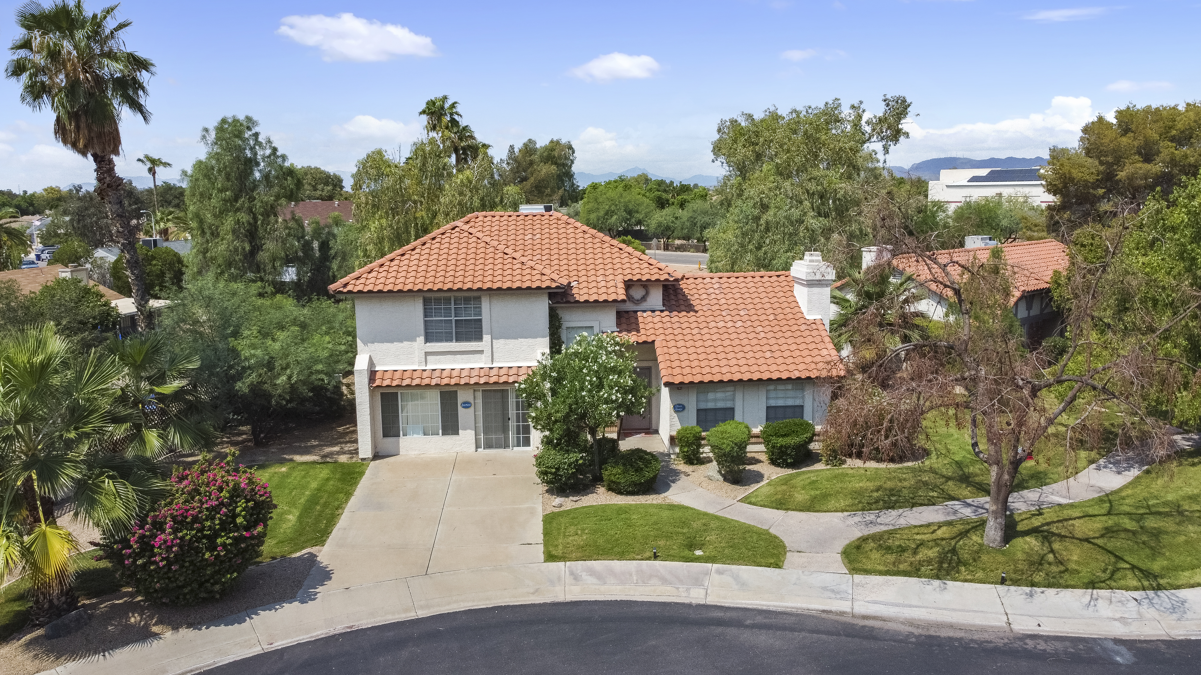 Two-story hoouse around greenery and a lawn.