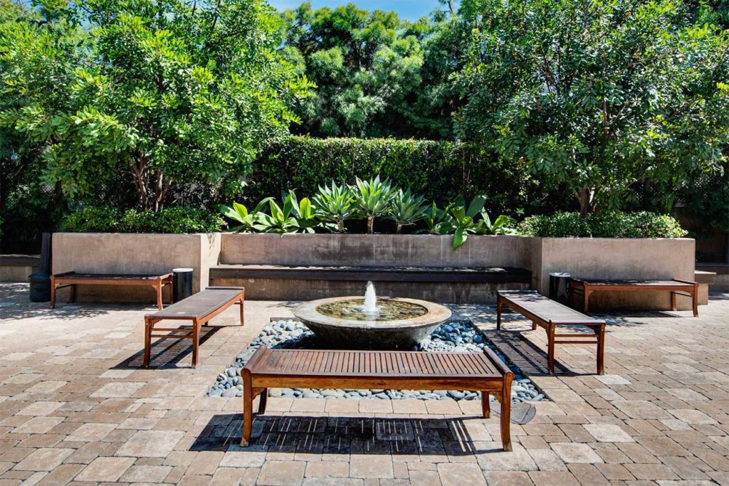 Outdoor zen garden with fountain and benches.