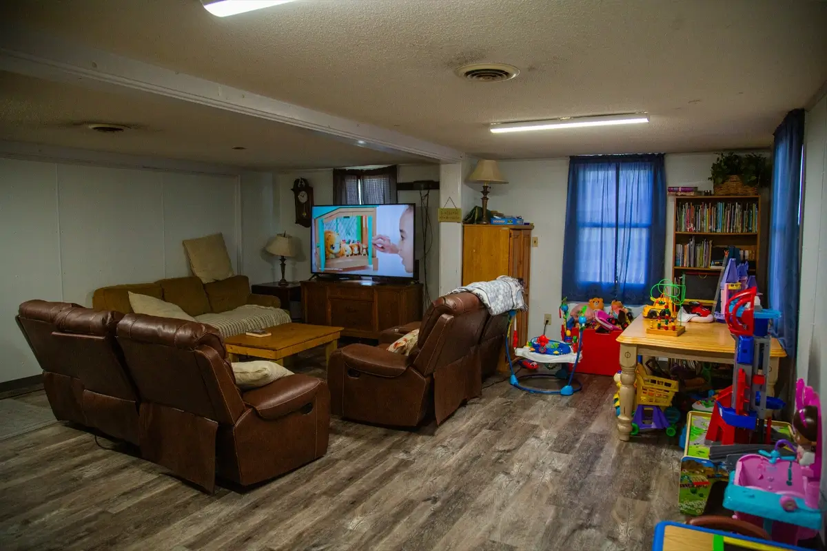 Basement family room with recliners, toys, and a TV playing kids’ show.