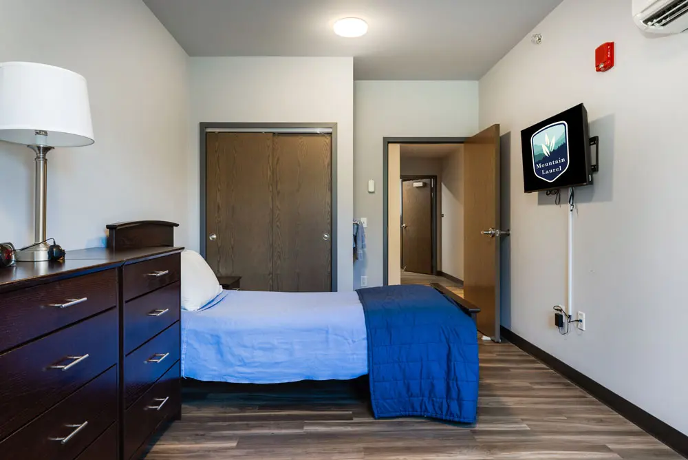 Private bedroom with bed, dresser, and wall-mounted TV