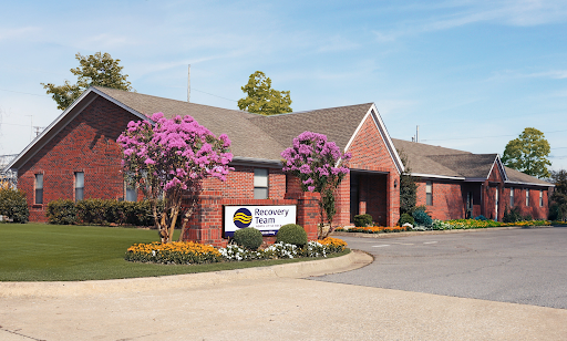 Side view of brick building surrounded by green lawn and trees.