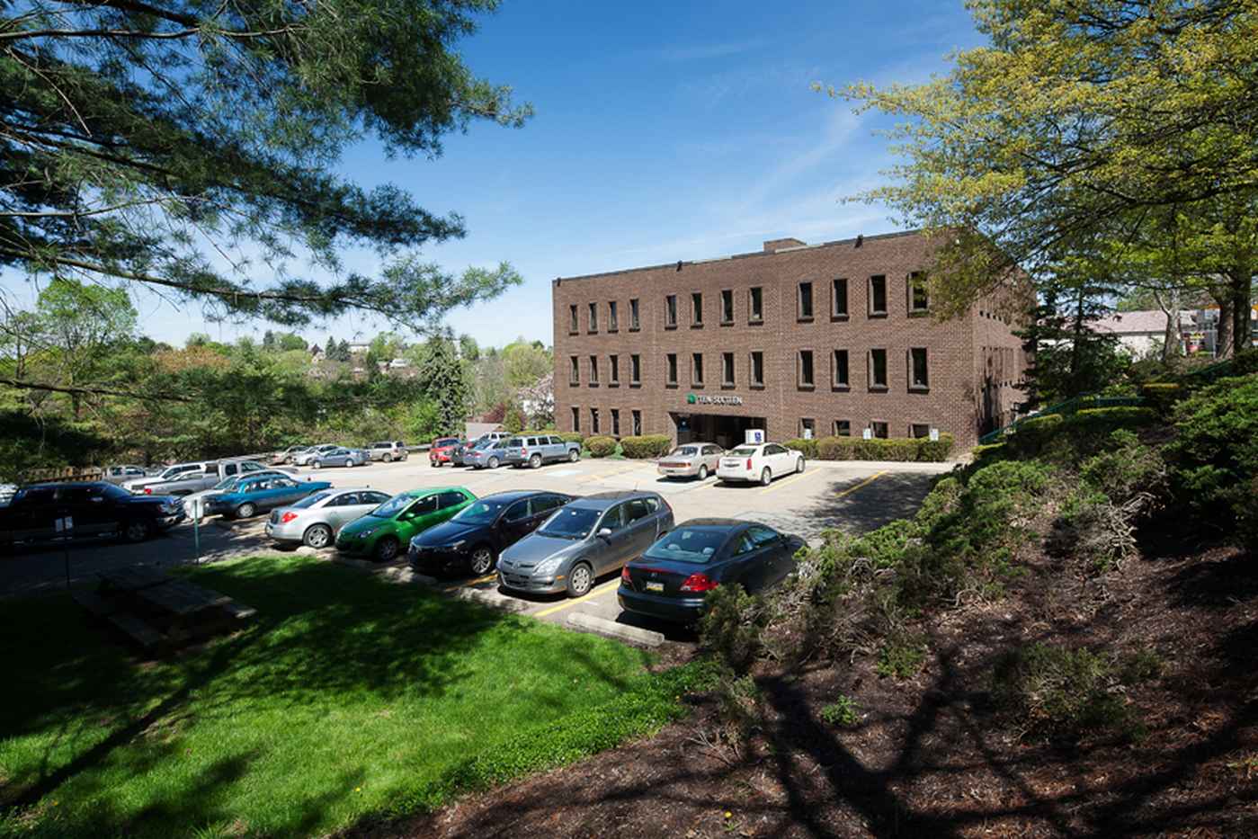 Brick rehab facility with parking lot and surrounding greenery.