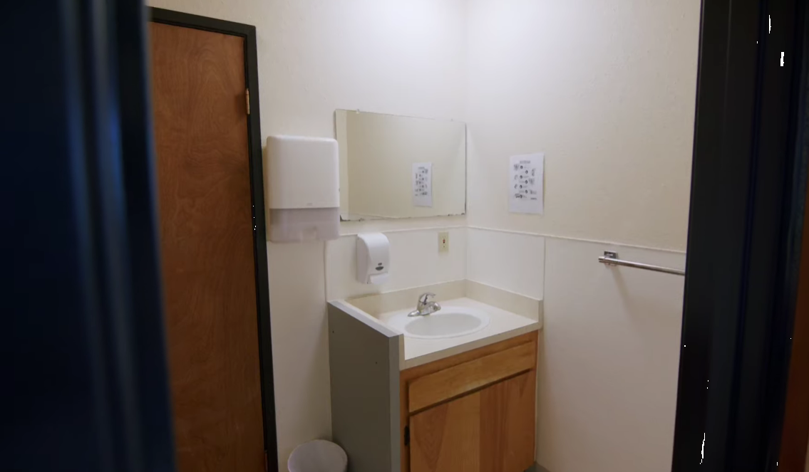 Clean bathroom with sink, mirror, and paper towel dispenser