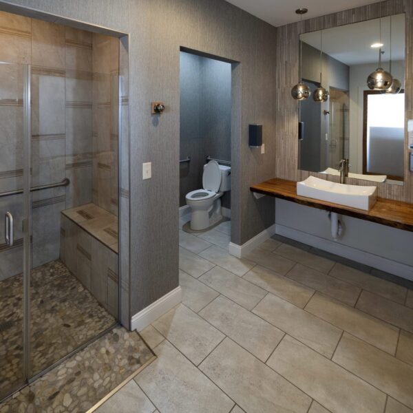 Modern bathroom with walk-in shower, toilet, and single-sink vanity at Bel Aire Recovery Center