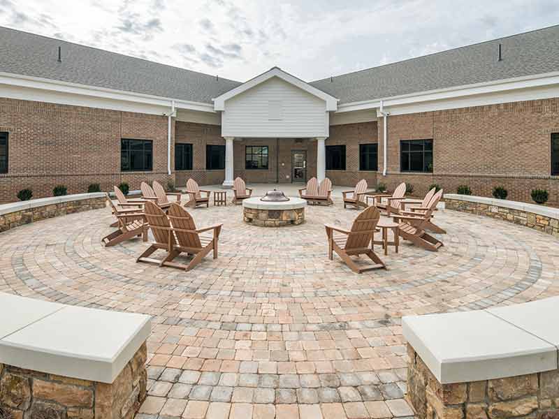 Outdoor courtyard with circular fire pit and Adirondack chairs at treatment center