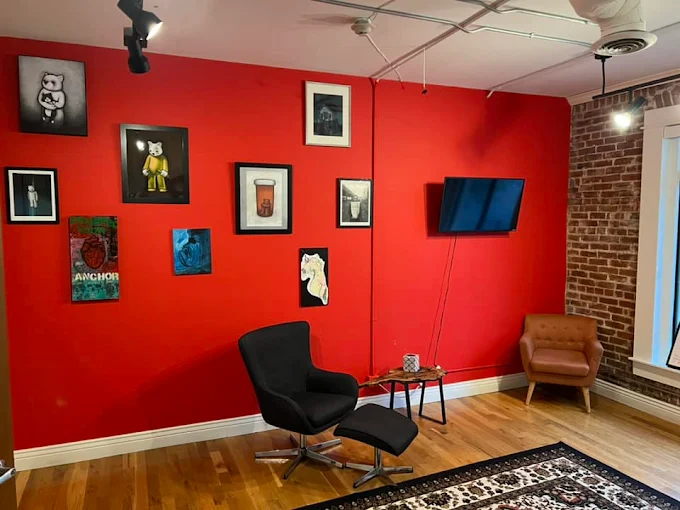 Lounge with red accent wall, art, and modern chairs