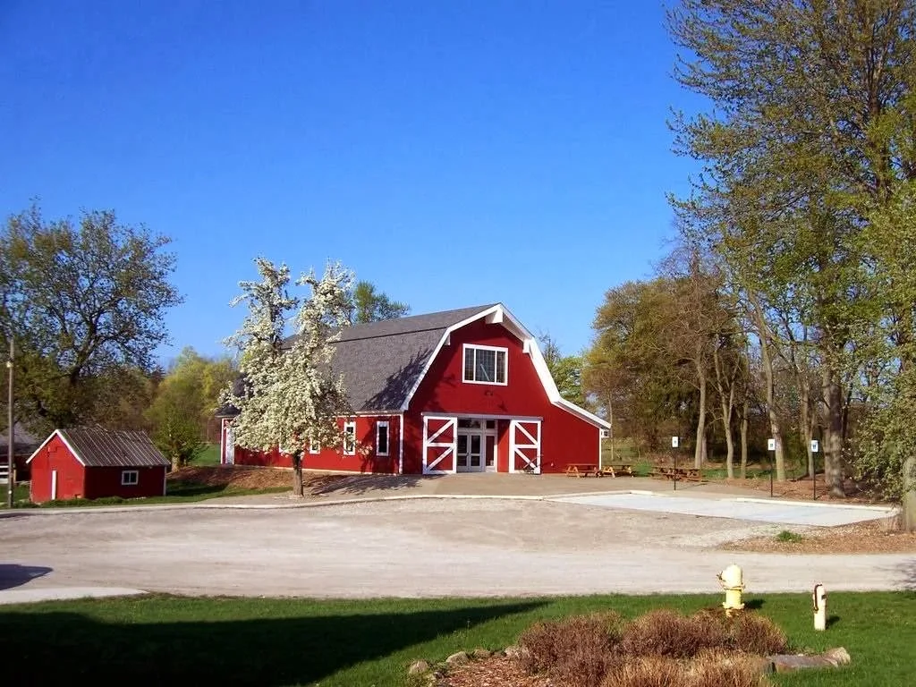 Large red barn surrounded by trees at Dawn Farm