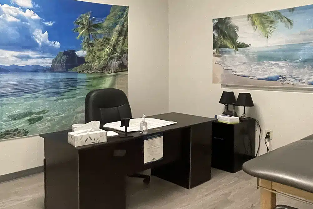 Office with desk, beach wall murals, and exam table