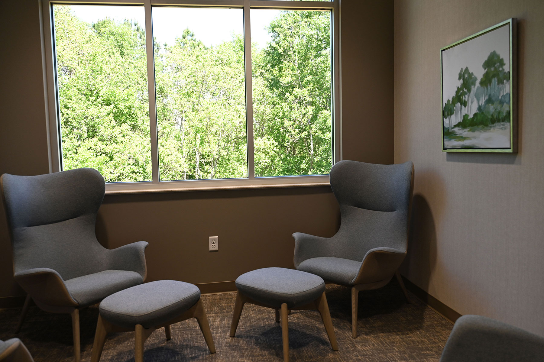 Quiet seating area with armchairs, ottomans, and windows