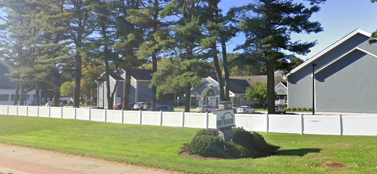 Rehab center exterior with white fence and tall pine trees