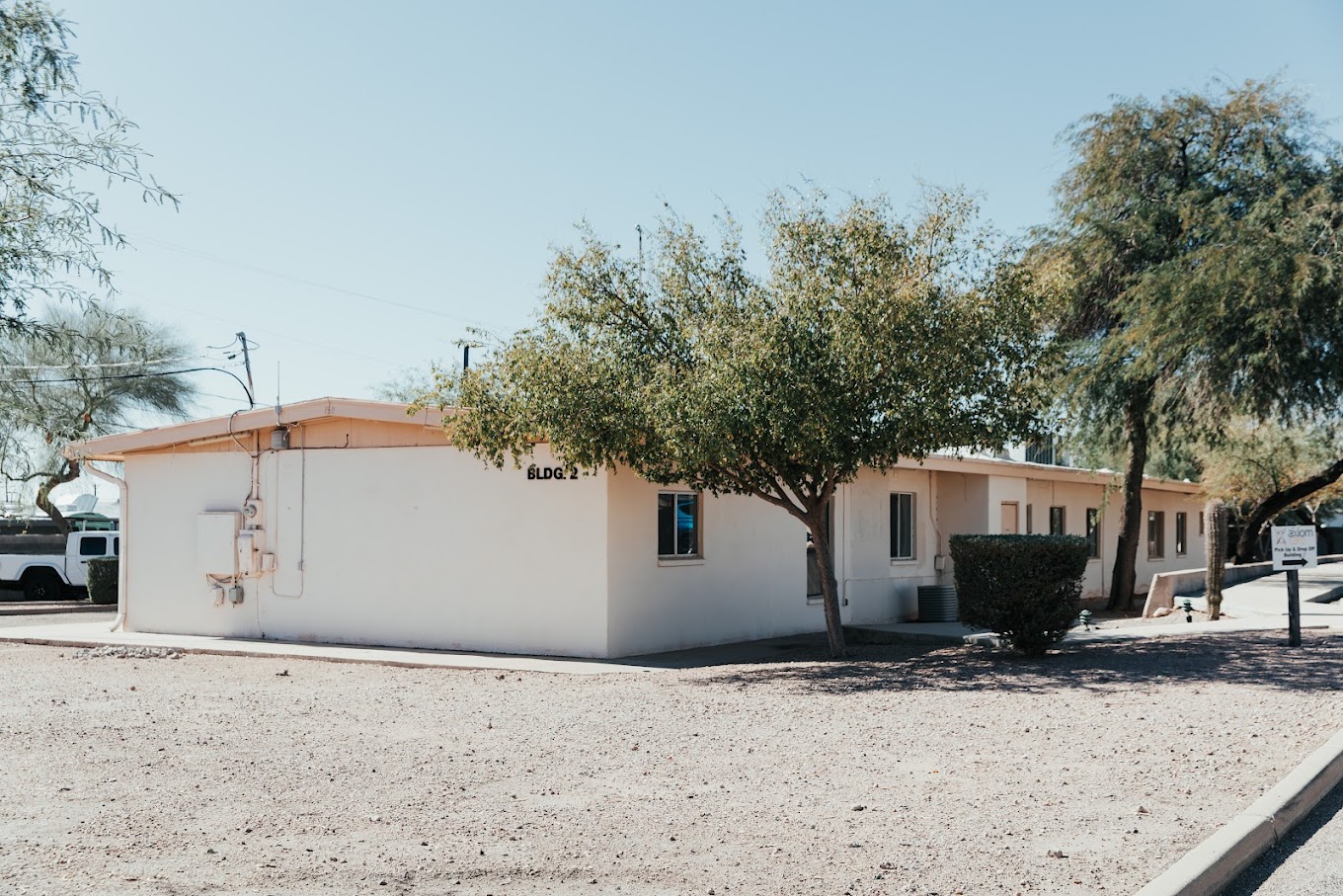 A single-story beige building with a flat roof and desert landscaping.