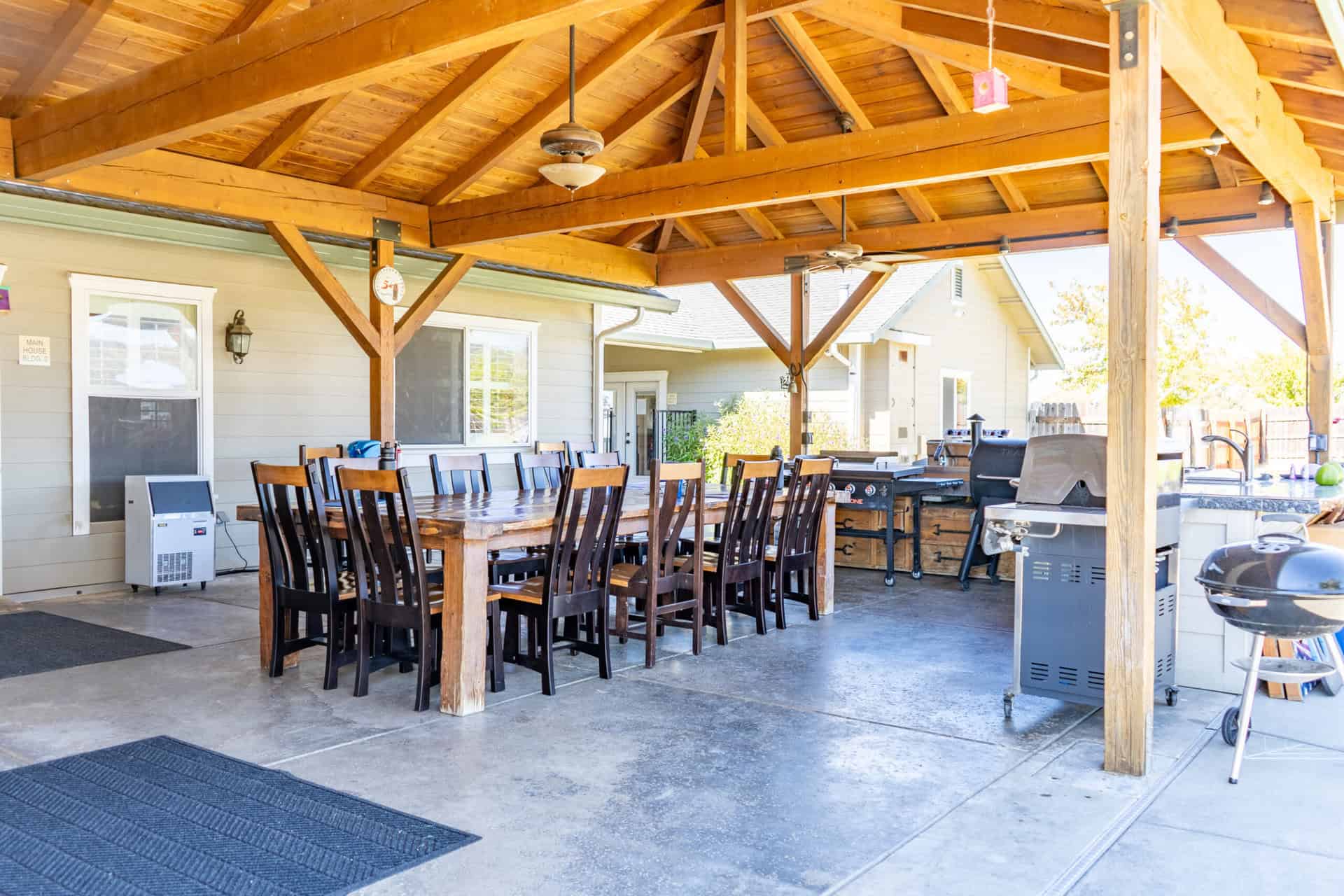 Covered outdoor dining area with long table and grills