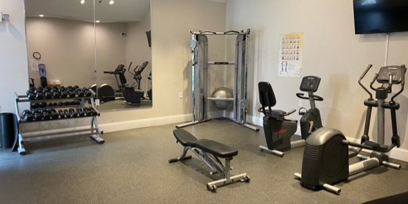 A well-equipped fitness room featuring exercise bikes, a weight bench, and free weights, providing a space for healthy, active living.