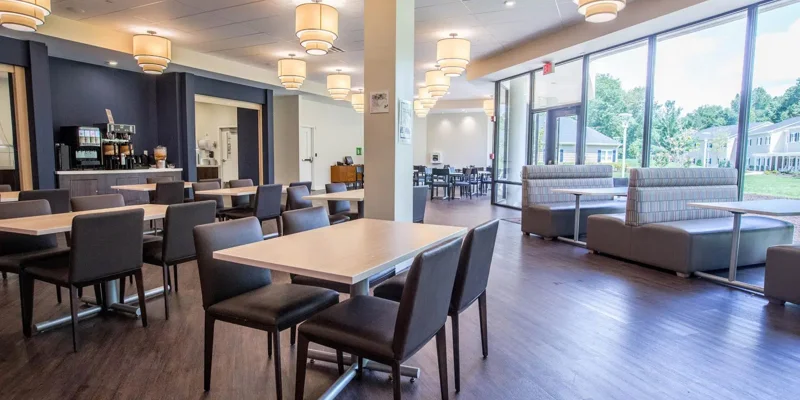 Spacious dining area with modern seating, large windows offering natural light, and elegant lighting, creating a comfortable and inviting atmosphere.