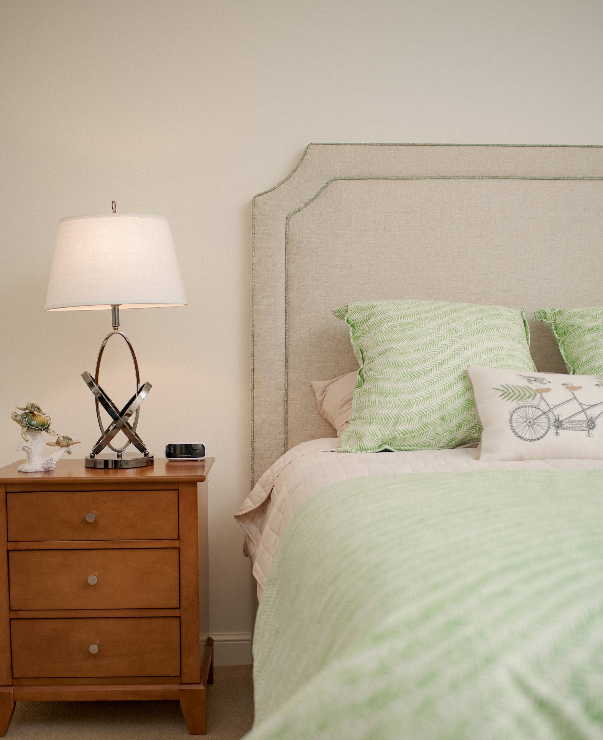 Cozy bedroom with light green bedding and wooden nightstand