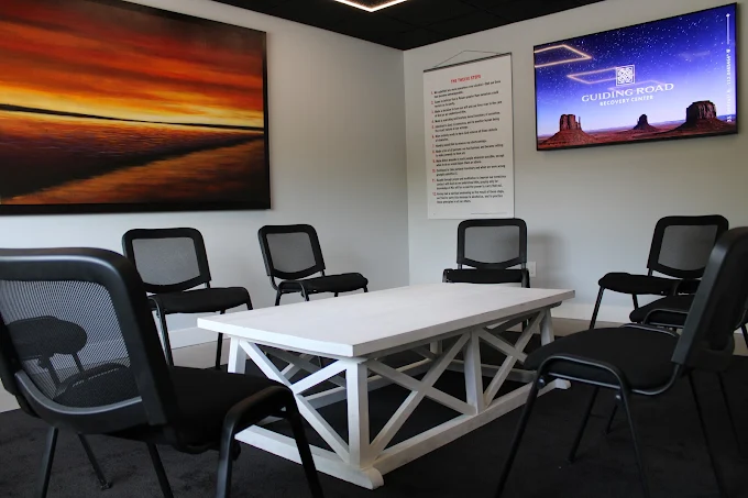 Circle of chairs around white table with wall screens