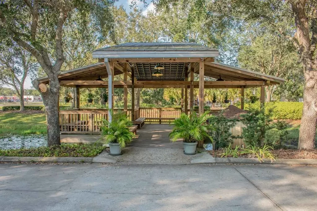 Wooden gazebo by pond surrounded by lush greenery