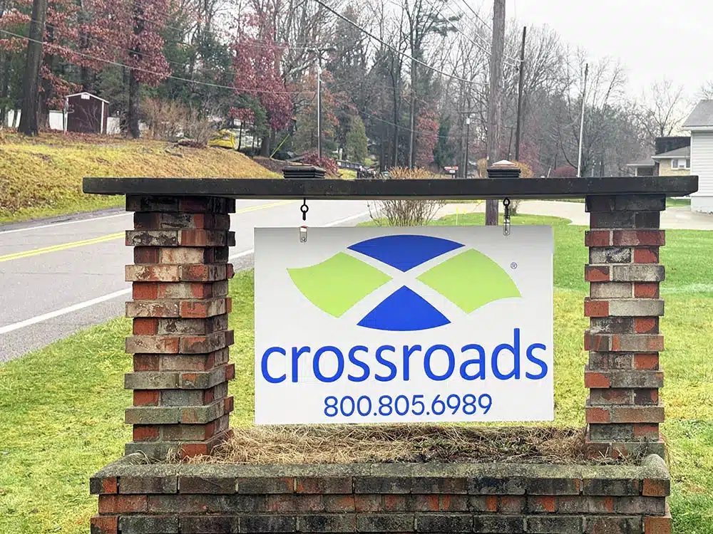 Crossroads sign with phone number beside roadside