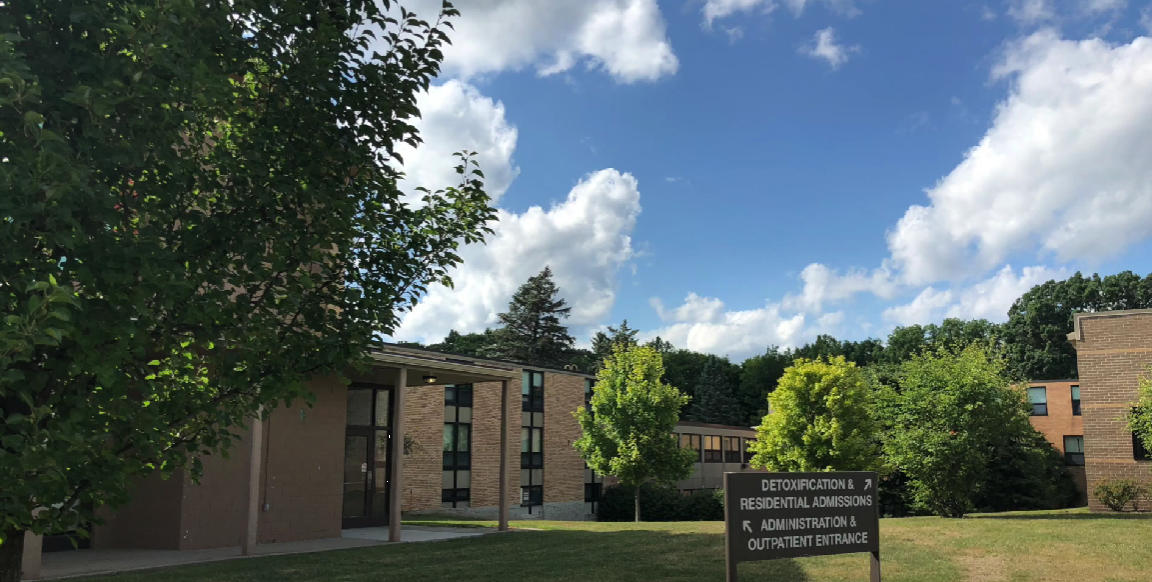 Brick facility with trees and sign for detox and admissions