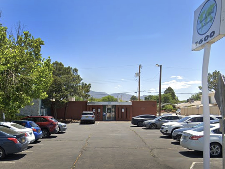 Small brown clinic building with parking lot and sign out front