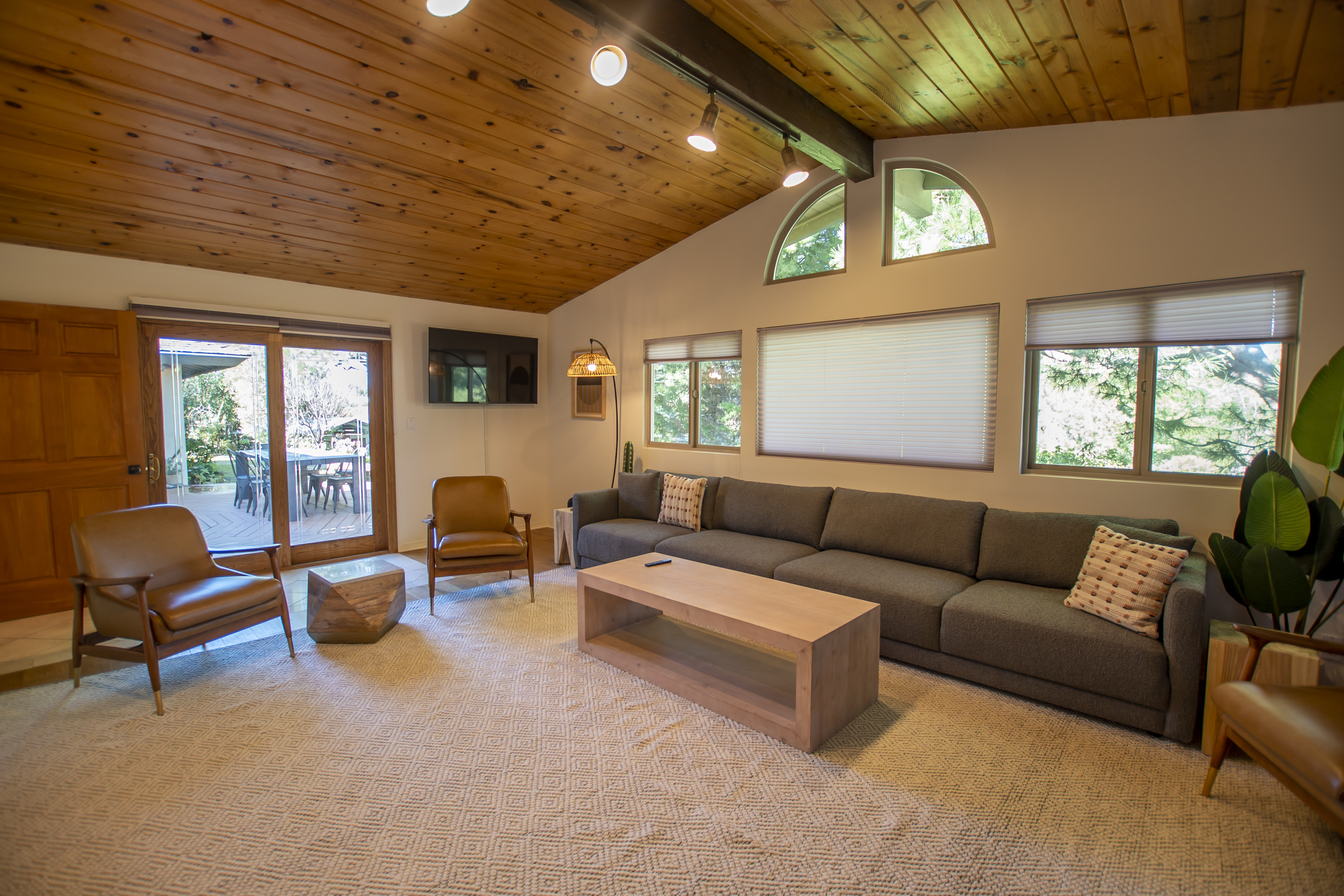 A living room with vaulted ceilings, large windows, and a gray sofa.