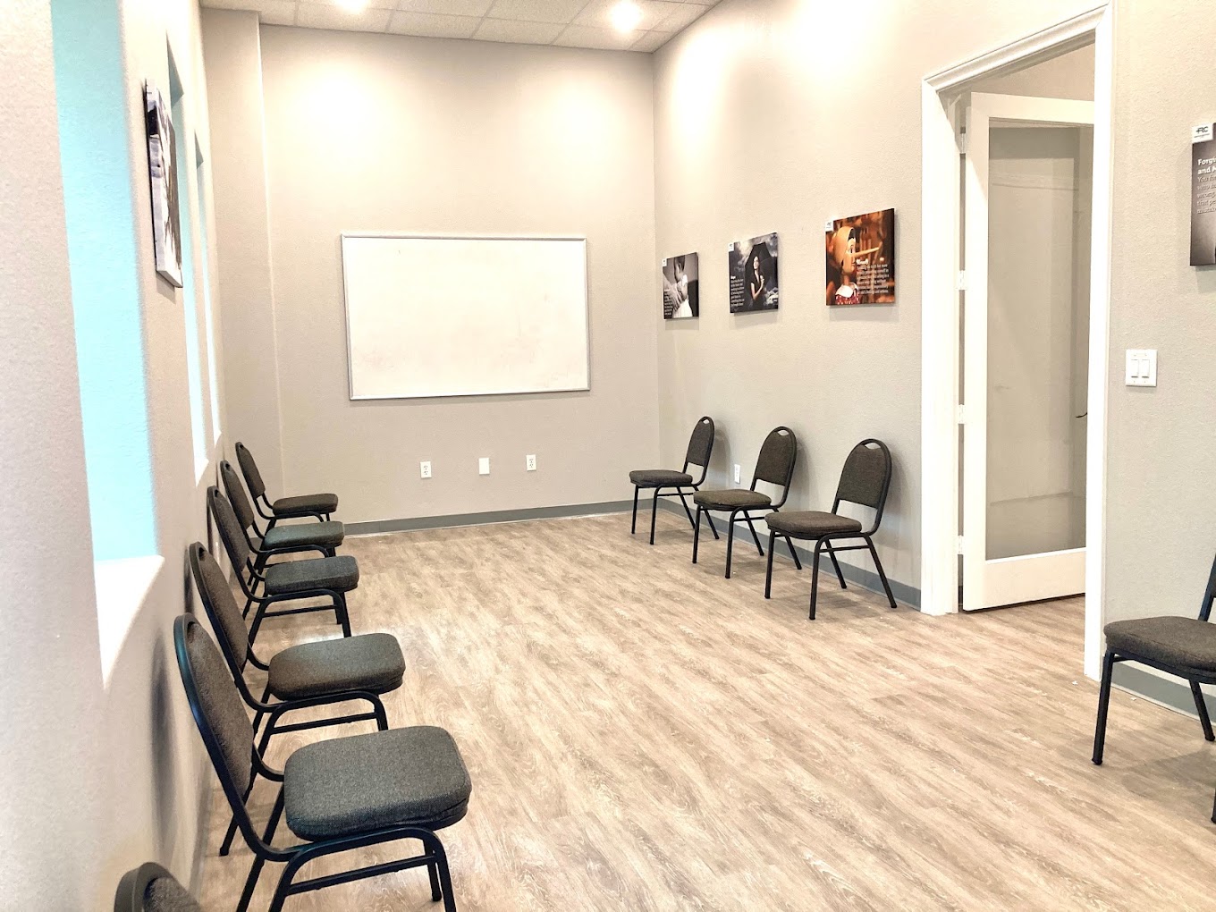 A bright group therapy room with chairs facing a whiteboard.