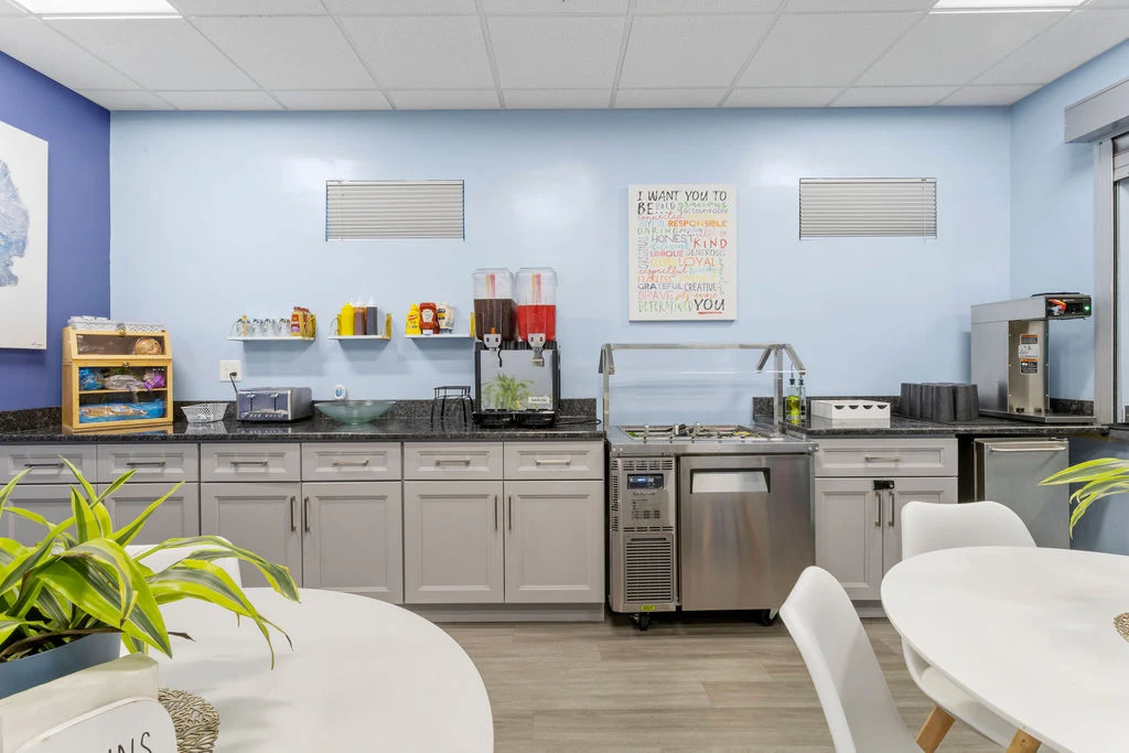 Beverage and snack station with light blue walls, dispensers, and kitchen counter