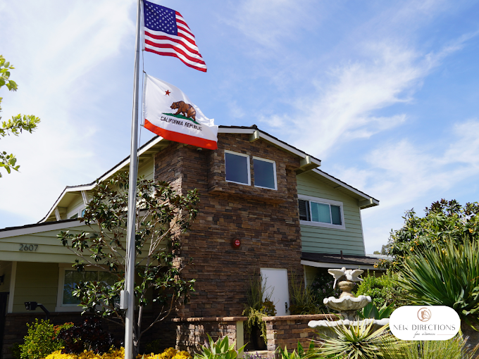 Two-story rehab center with fountain and flags in front yard