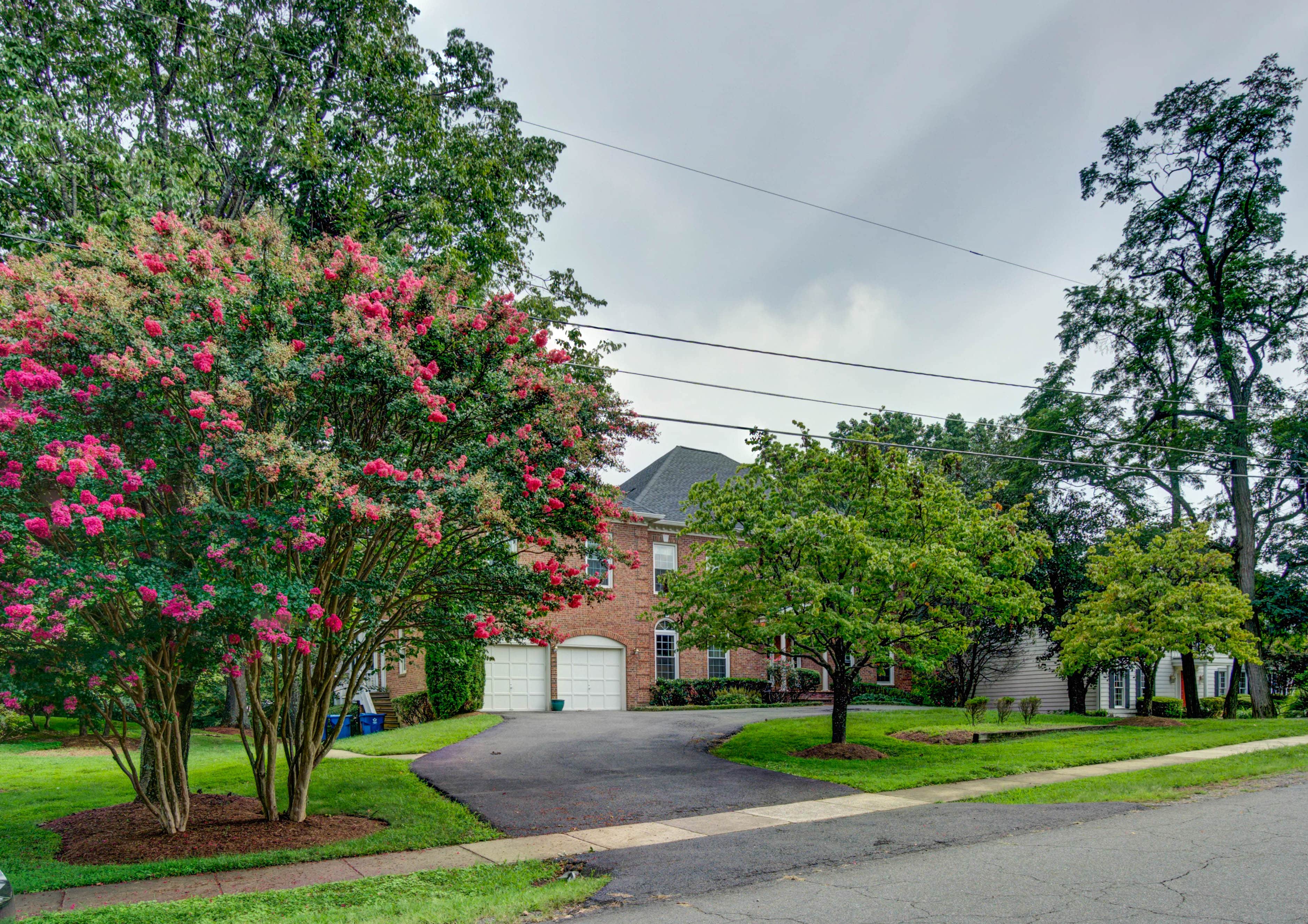 Brick house with driveway and blooming pink trees