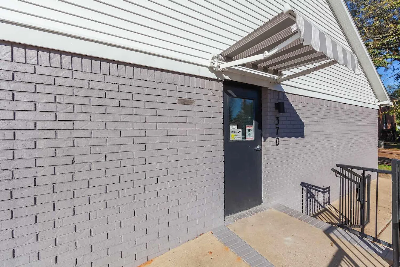 Facility entrance with awning, steps, and safety railing
