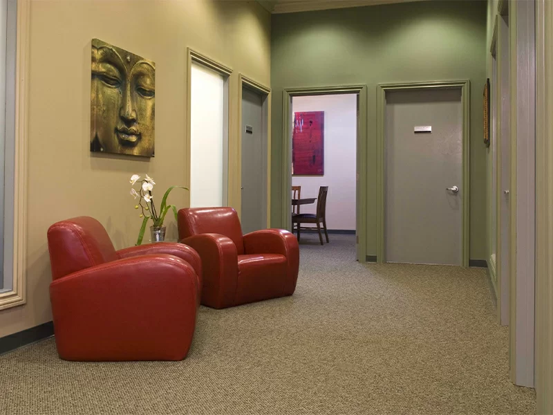 Quiet hallway with red chairs, soft lighting, and calming wall art