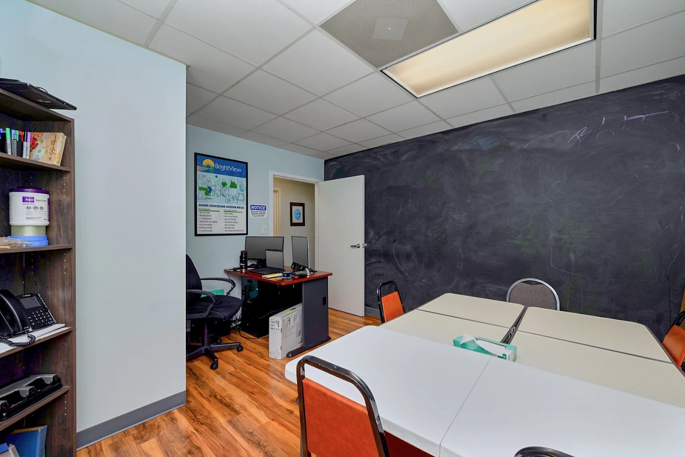 Group therapy room with tables, chairs, and chalkboard wall