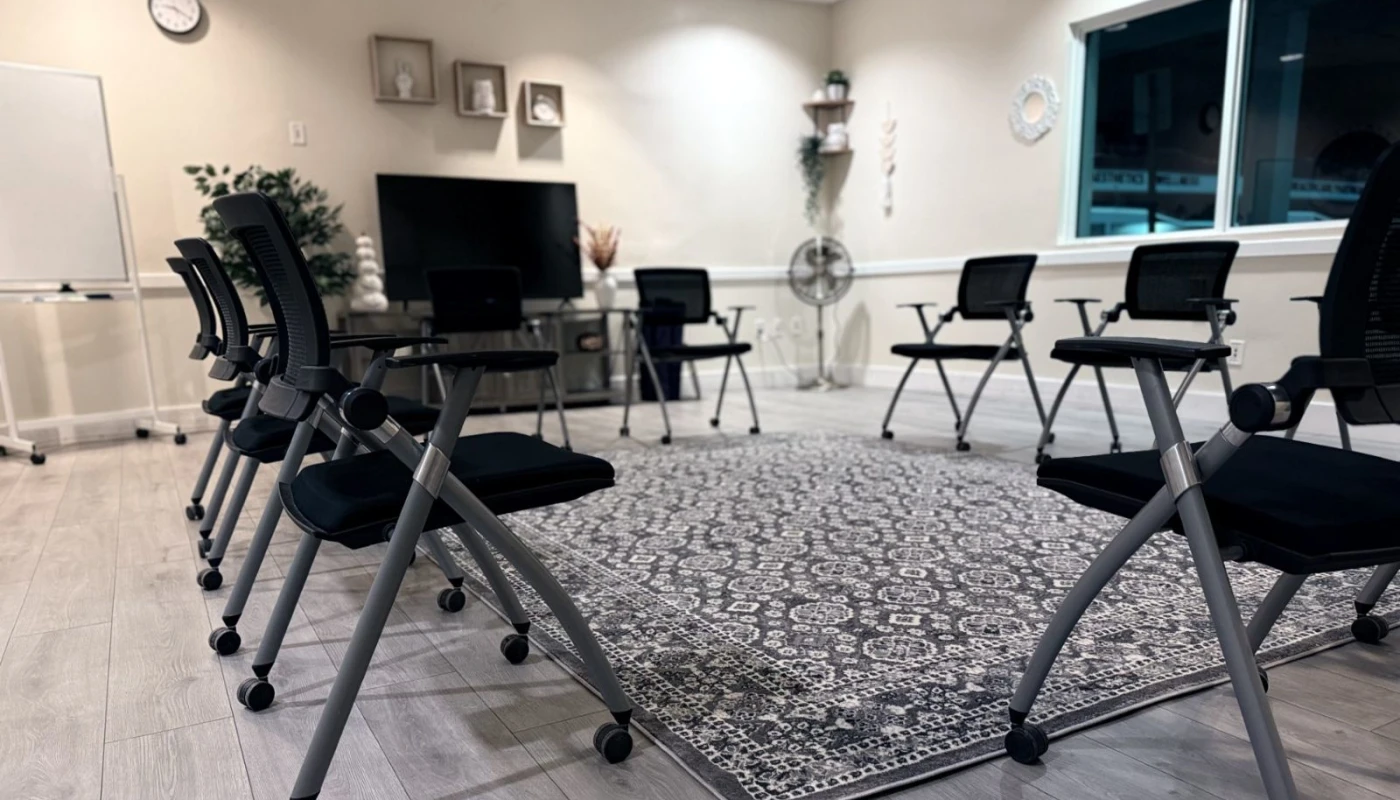 Therapy room with rolling chairs, a TV, and wall decor.