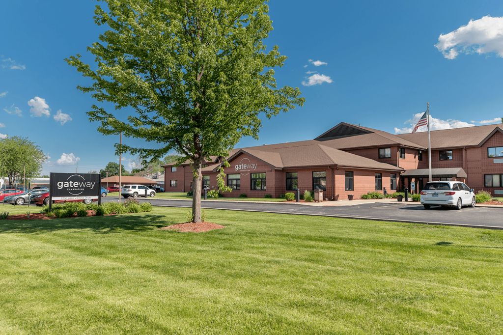 Red brick building with landscaped lawn and parking area