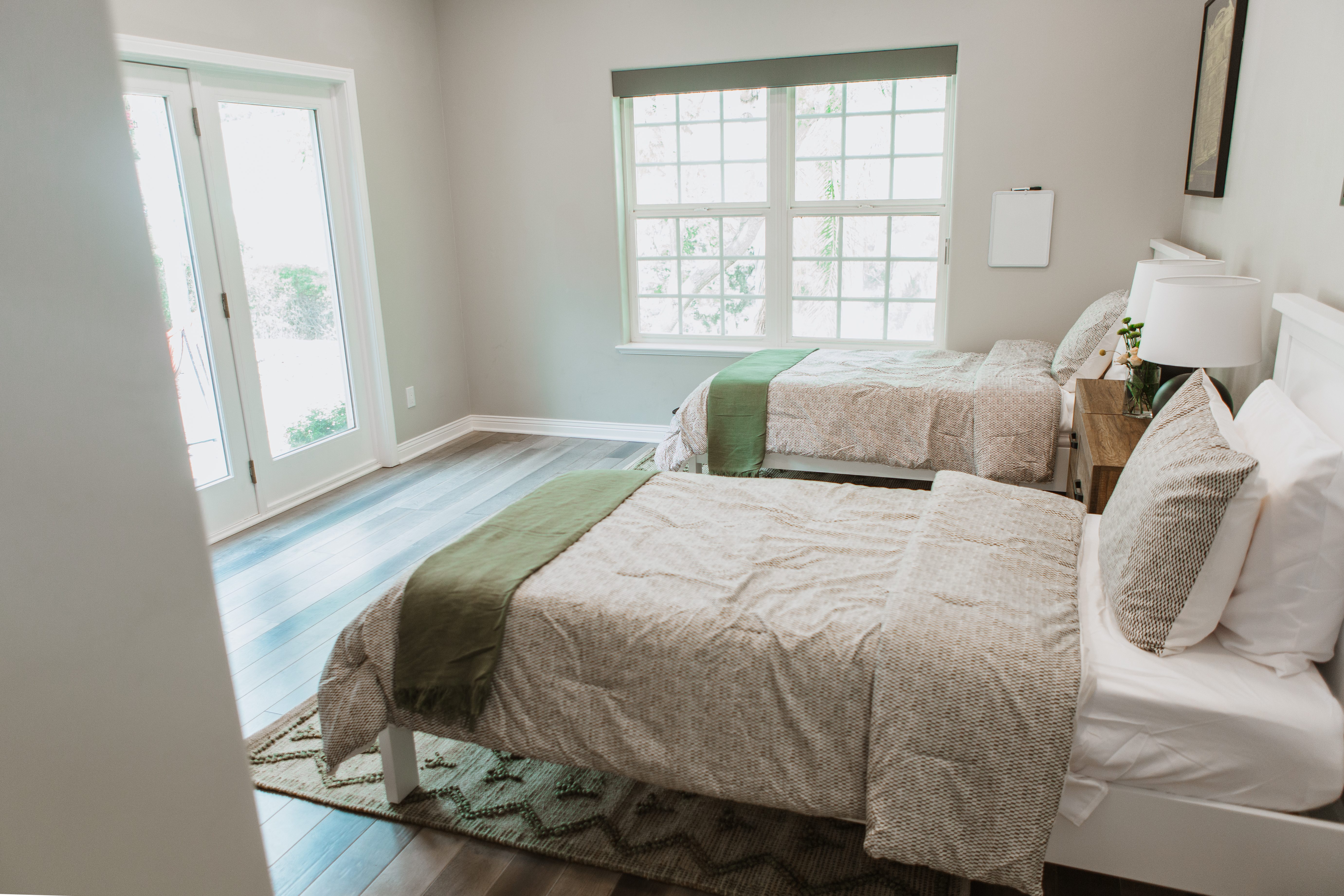 Room with two beds and large window near patio door